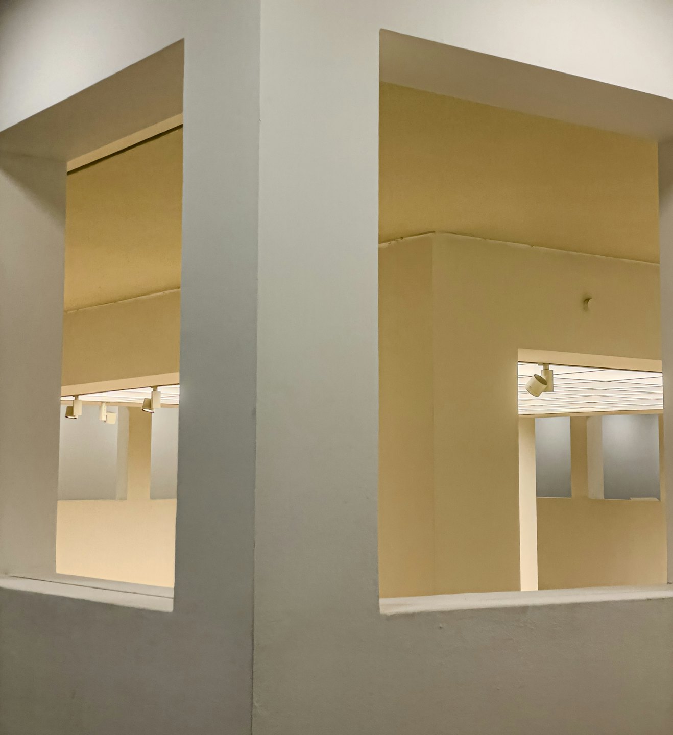 Sich kreuzende hellgraue Wände mit geometrischen Türen geben den Blick auf beige Räume frei.